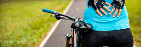 Vrouw met rugpijn tijdens fietsen die langs de weg staat