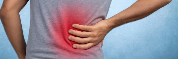 Persoon met hand op onderrug in koude omgeving, met subtiele warmte rond de rug om het contrast tussen kou en ontspanning te tonen.