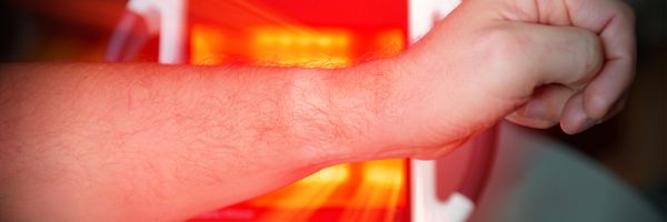 Illustratie van gewrichten in de hand met pijnpunten en een vrouw die infrarood handschoenen gebruikt voor diepe warmte, betere doorbloeding en minder stijfheid.
