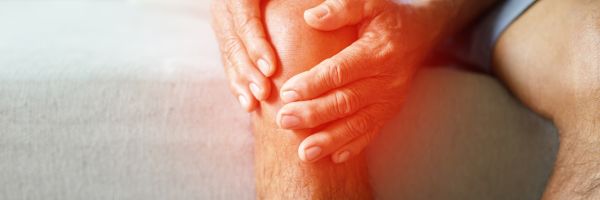 Oudere man houdt pijnlijke knie vast door artrose in de knie of gewrichtsklachten